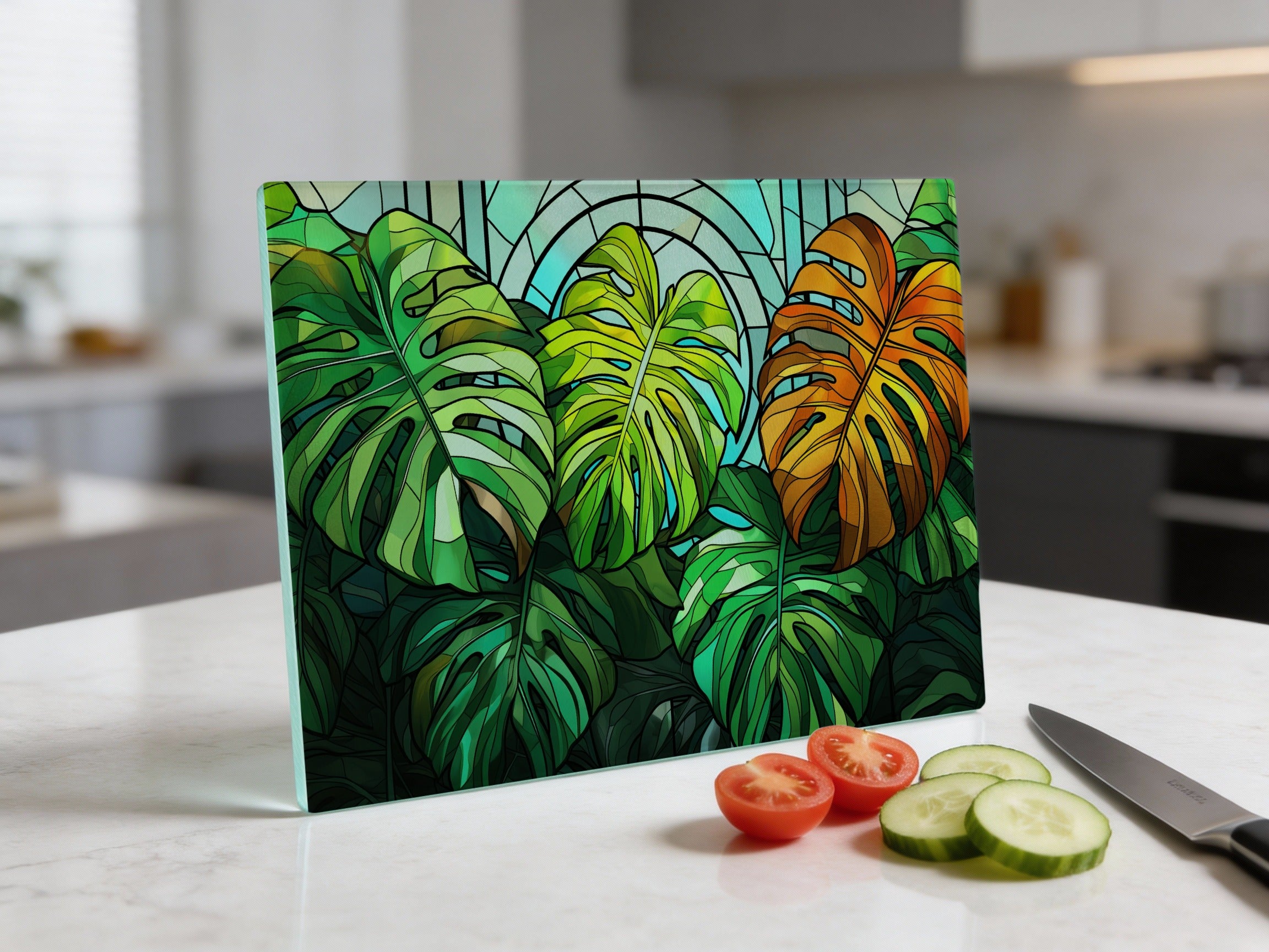 Stained glass cutting board with monstera leaves and kitchen counter with tomatoes and cucumber.