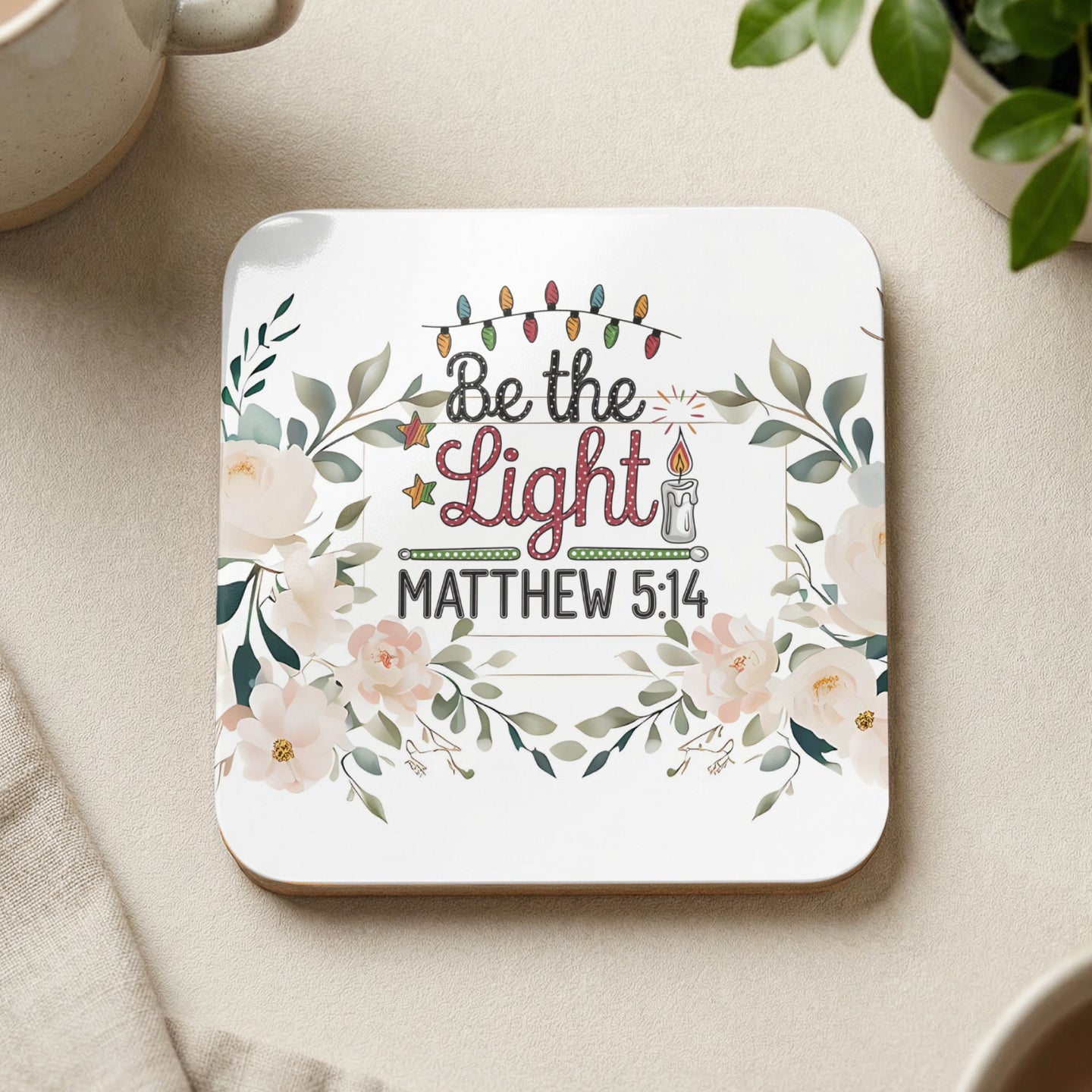 Square coaster with floral design, Christmas lights, and "Be the Light Matthew 5:14" text.