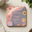 Coaster with "Happy Mind Happy Life" text surrounded by flowers and a rainbow.