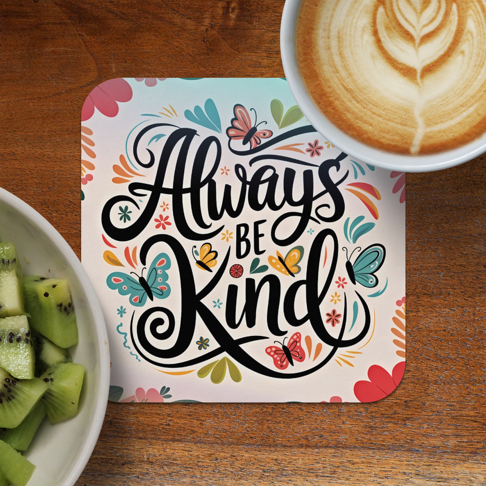 Always be kind sentiment on coaster with coffee and kiwi fruit.