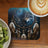 Wolf dreamcatcher with feathers, coffee, and kiwi fruit on wooden table.