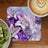 Lilies and purple butterflies on a patterned coaster next to kiwi fruit and coffee.