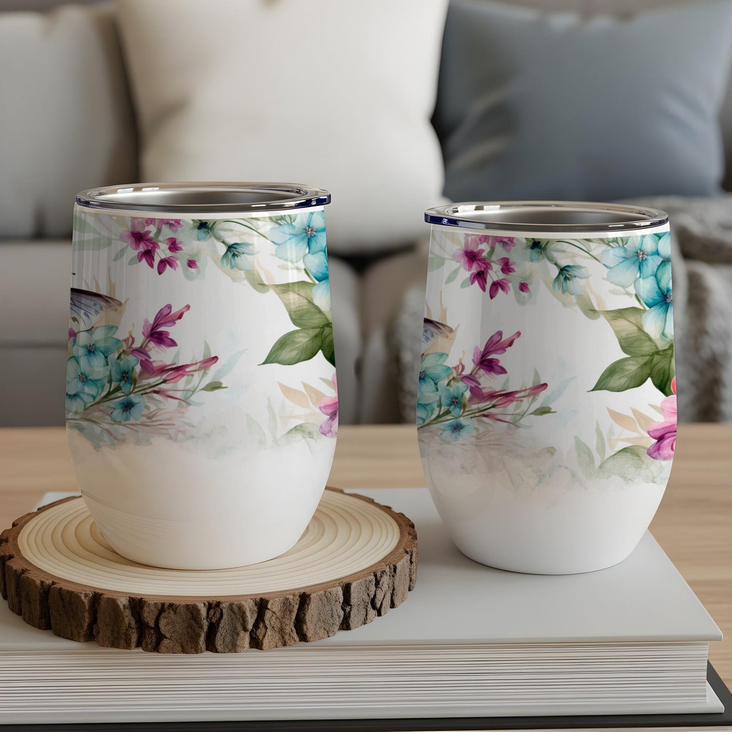 Two stemless wine tumblers with floral and butterfly designs.