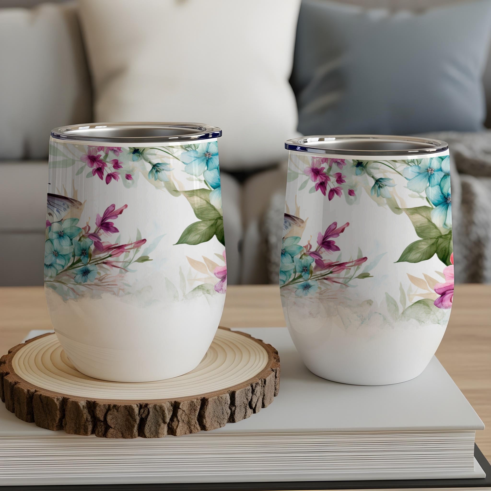 Two stemless wine tumblers with floral and butterfly designs.