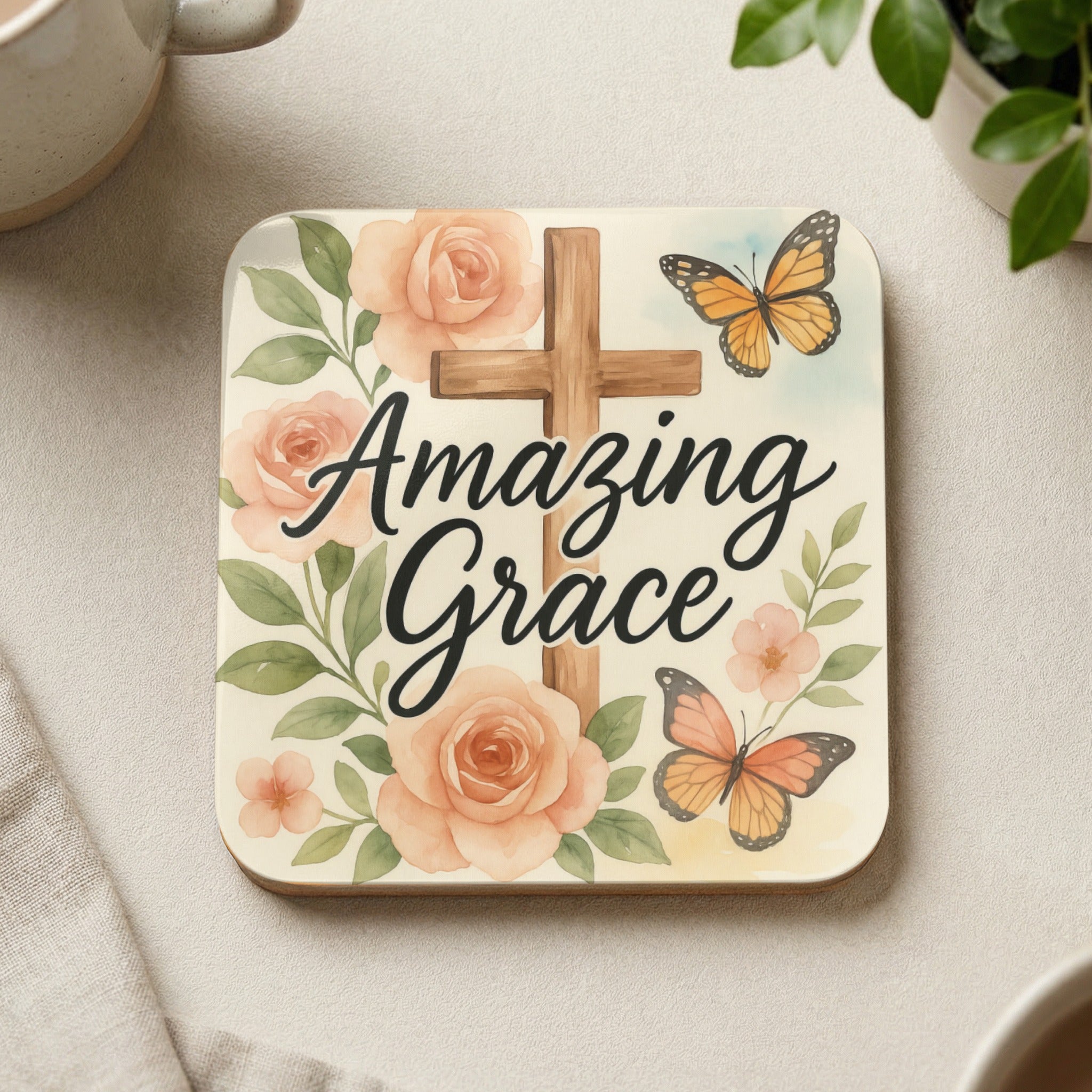 Square coaster with a wooden cross, pink roses, and two butterflies.