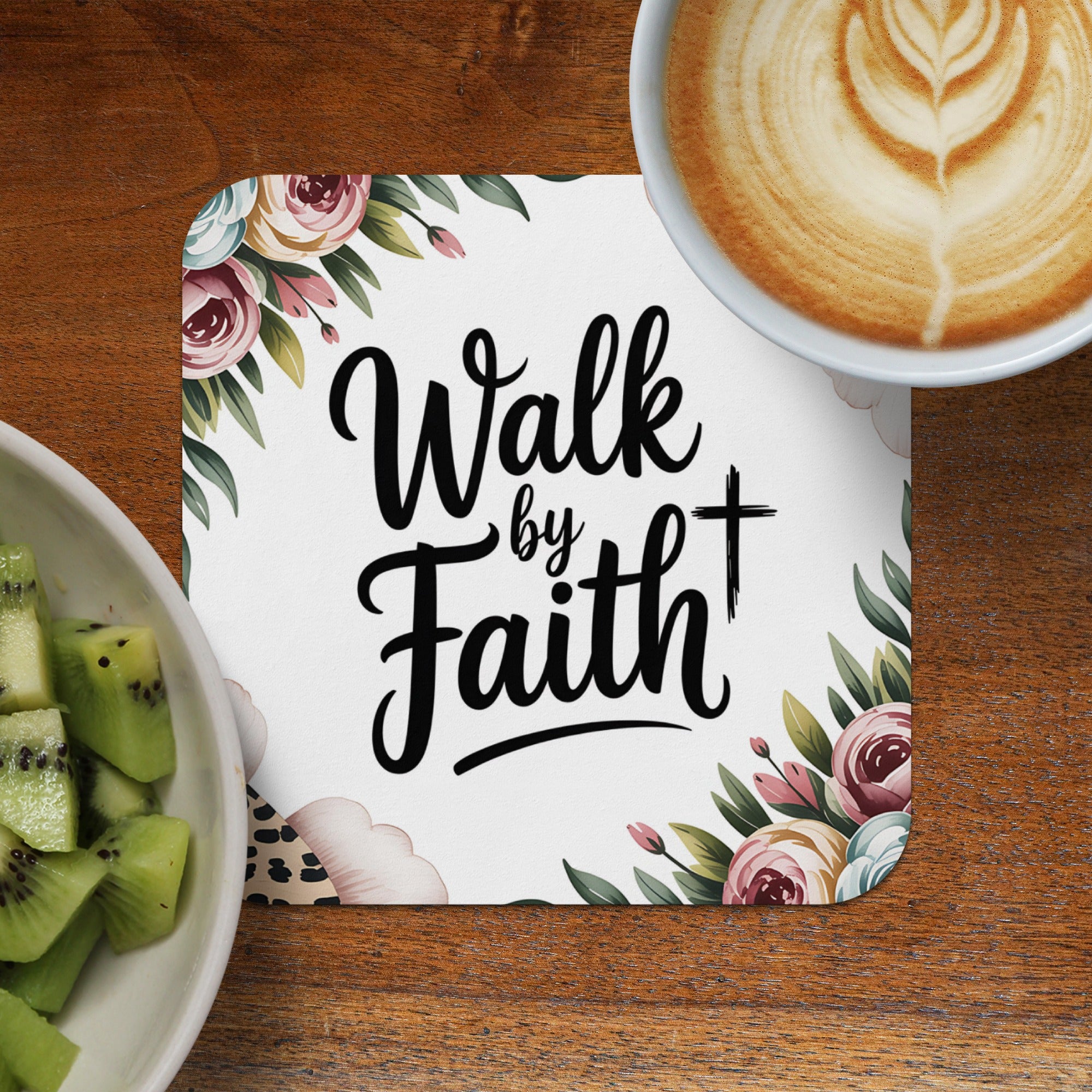 "Walk by Faith" quote on a coaster with floral accents, next to coffee and kiwi.