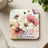 Square coaster with pink and white cosmos flowers and ladybug, "Love grows here" text.