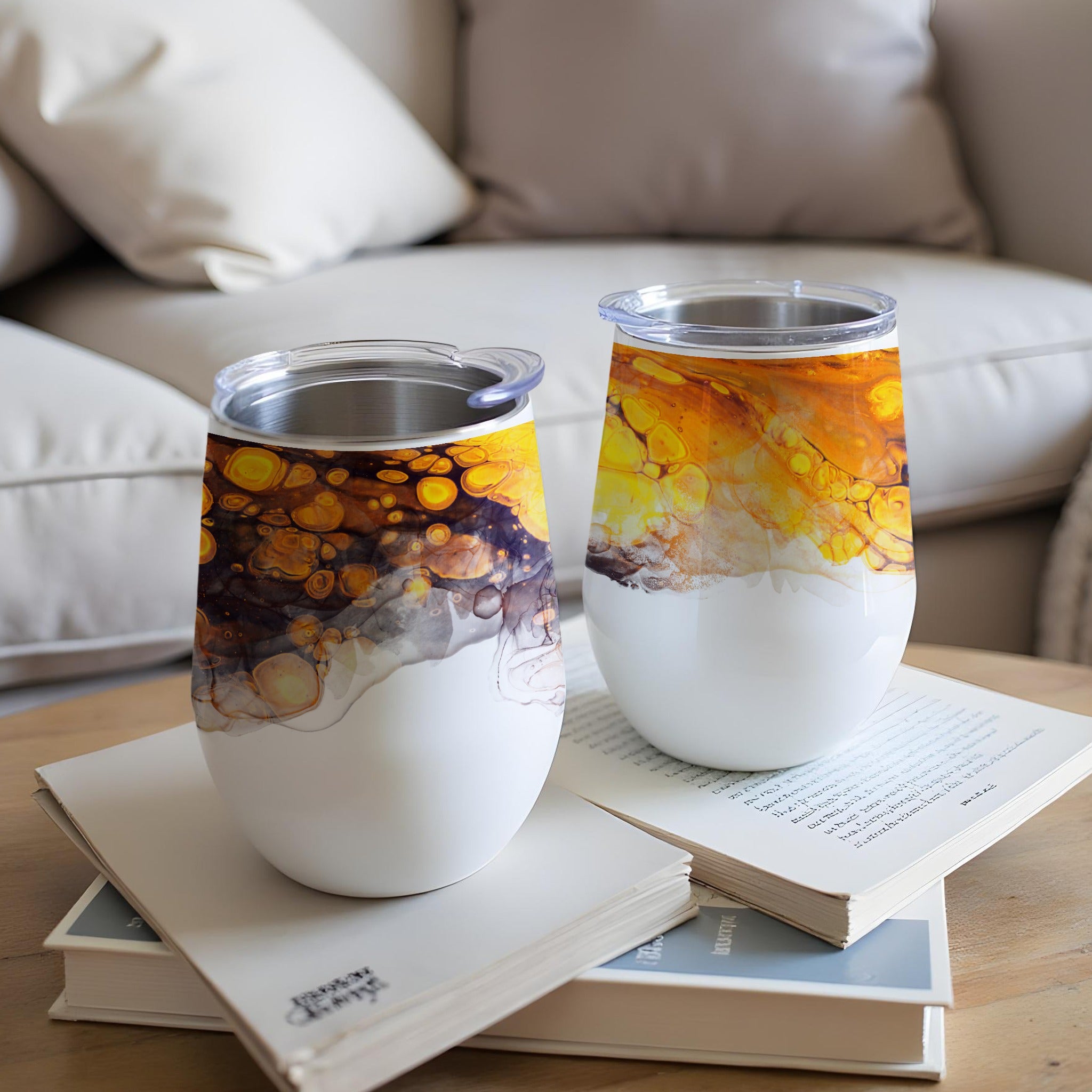 Two white tumblers with abstract yellow and orange marbling patterns.