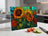 Glass cutting board with vibrant sunflowers and green leaves.