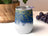 White tumbler with blue and gold glitter pattern, purple grapes nearby.
