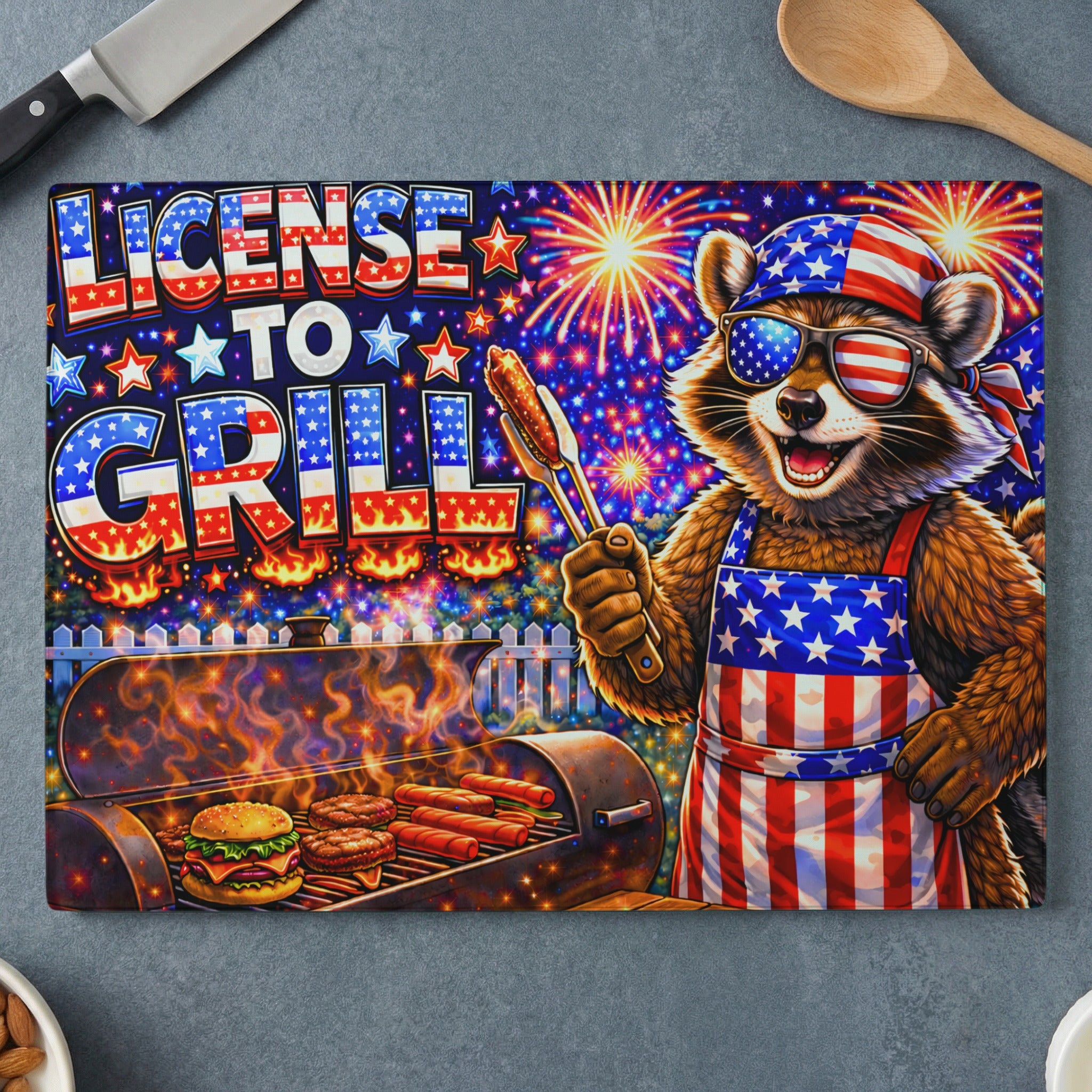 Raccoon in sunglasses and apron holding tongs at grill, "License to Grill" text.