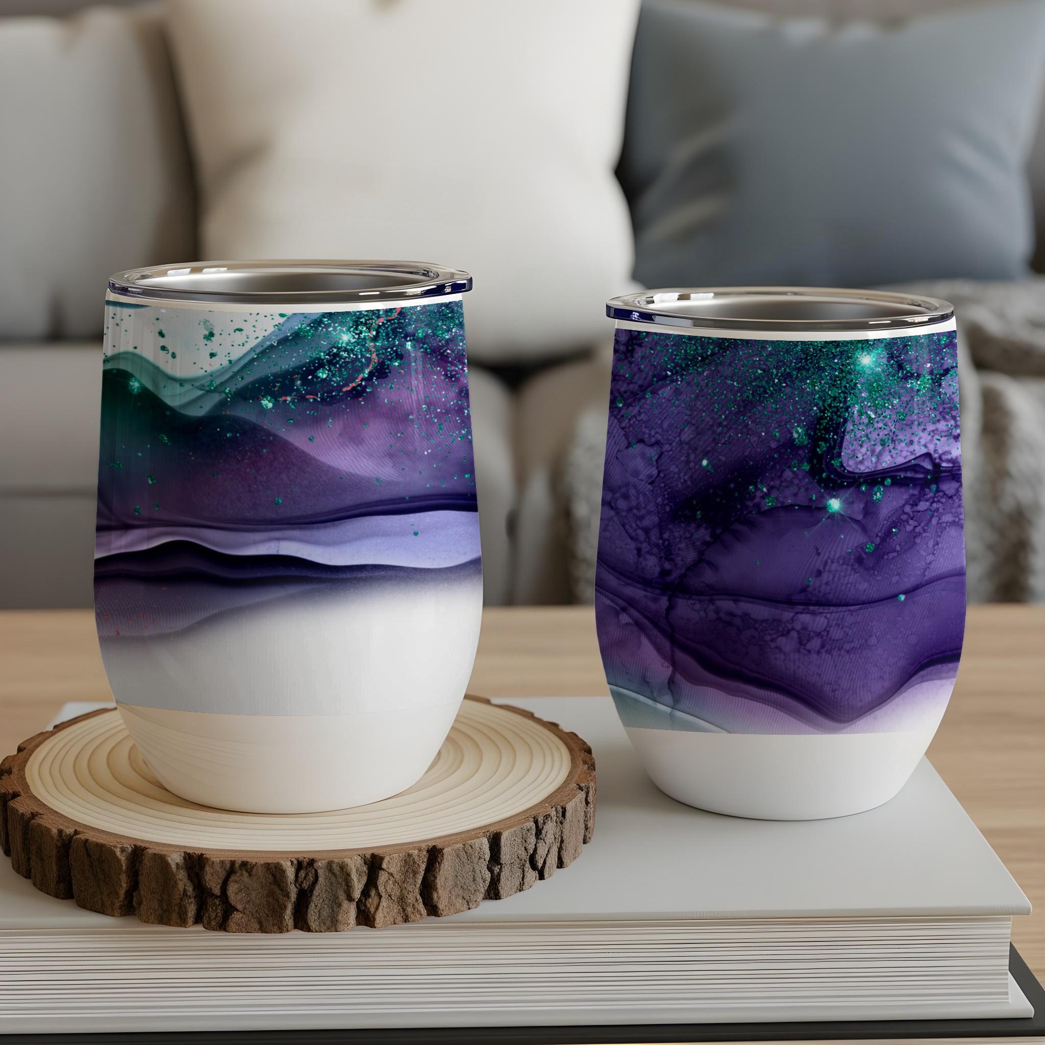 Two abstract art stemless wine glasses with purple, green, and blue swirling designs.