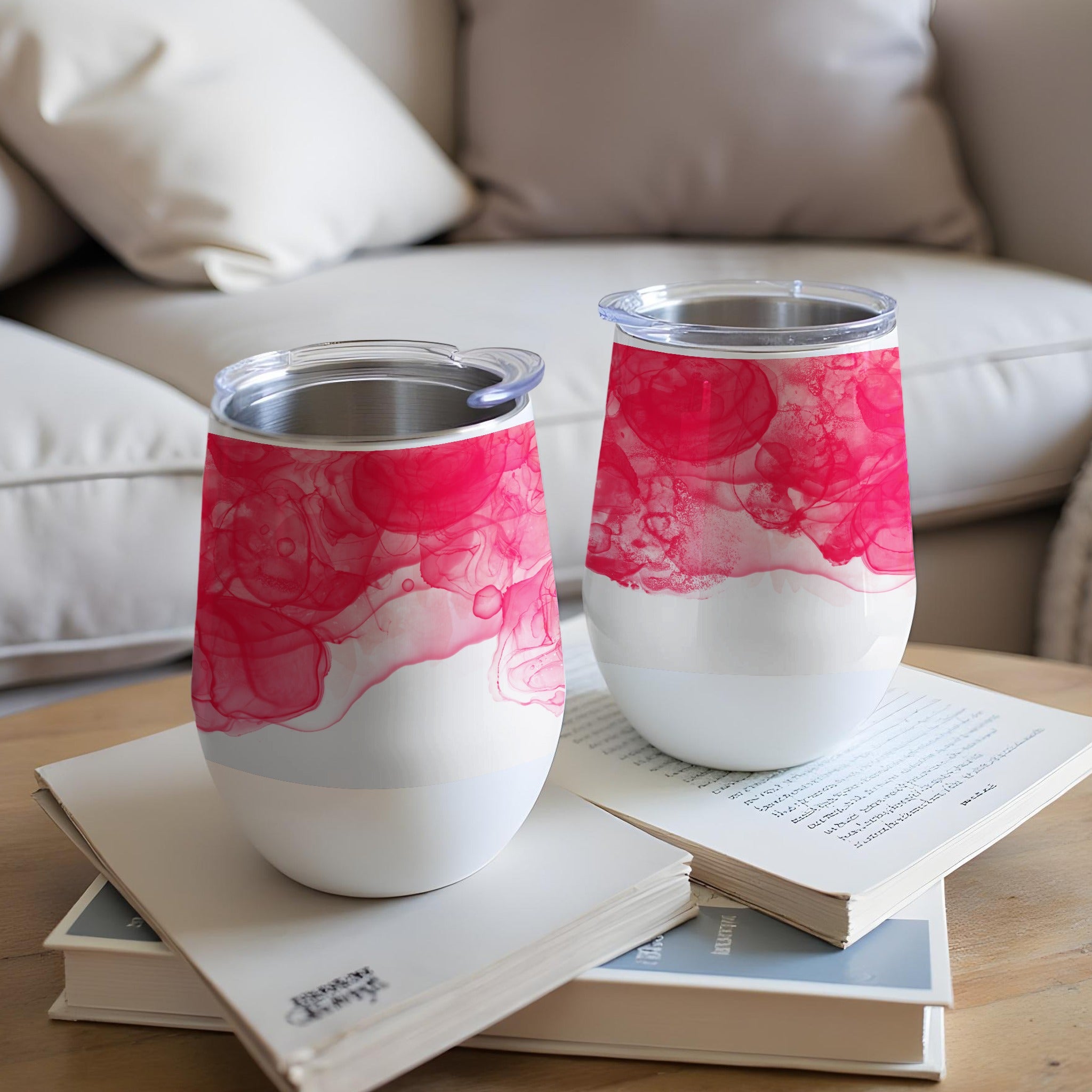 Two white tumblers with pink watercolor patterns rest on books.