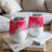 Two white tumblers with pink watercolor patterns rest on books.