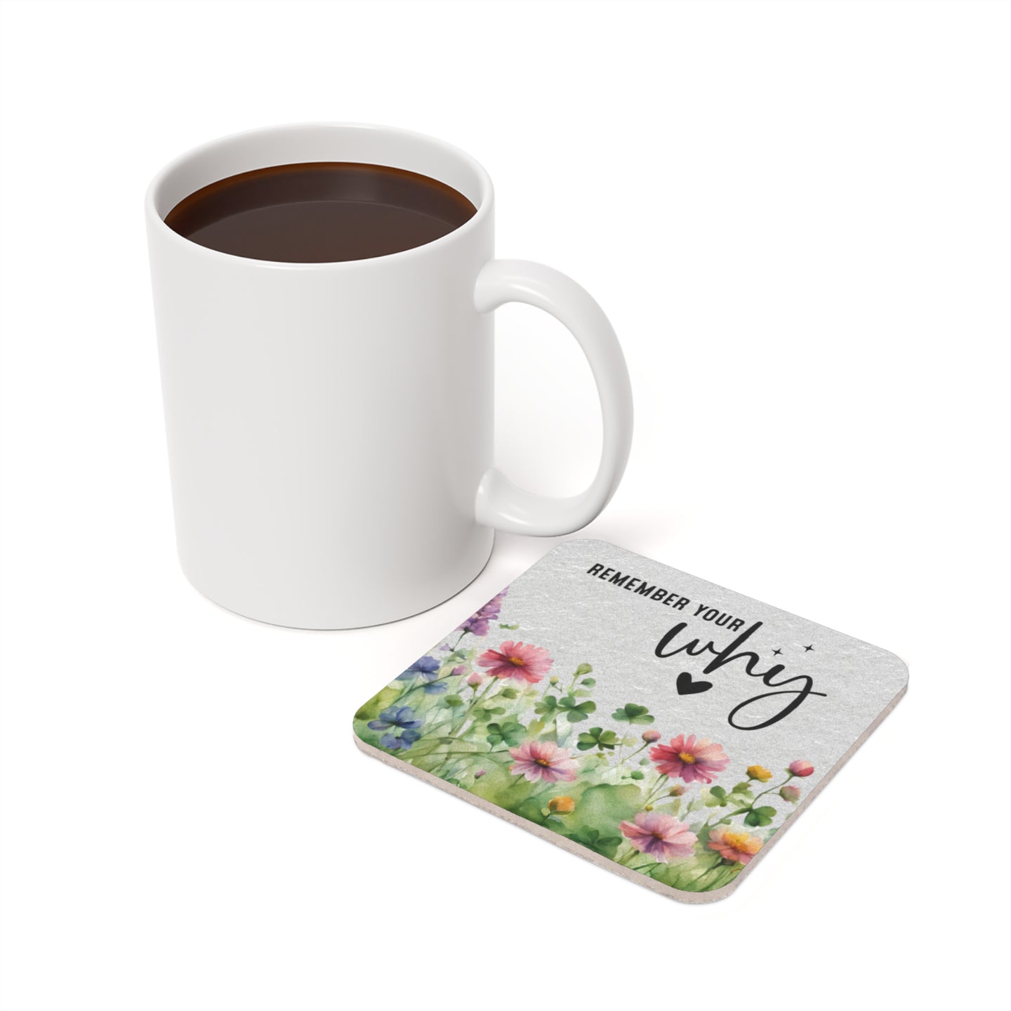 White mug with coffee next to a floral coaster with text REMEMBER YOUR why.