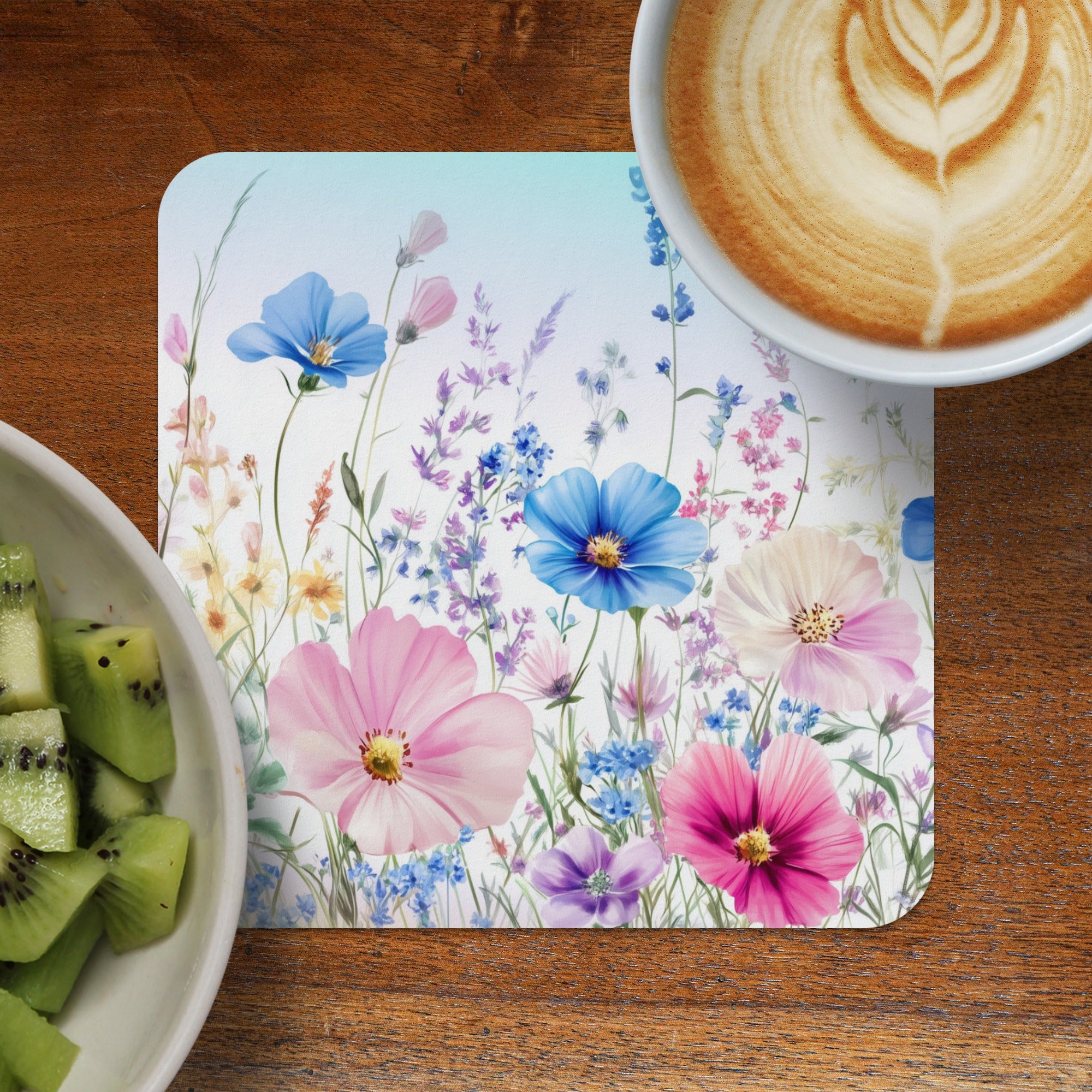 Floral placemat with coffee and kiwi slices on a wooden table.