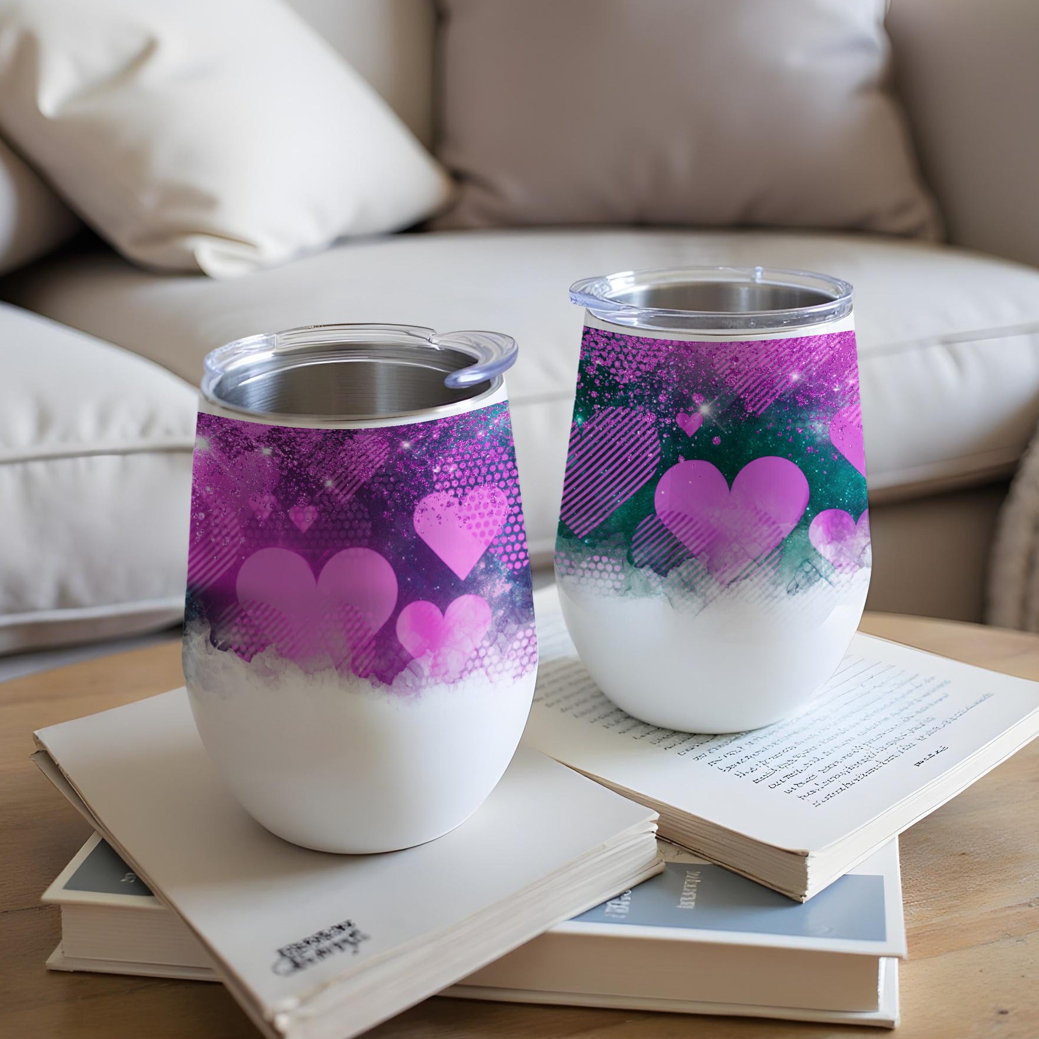 Two purple heart-patterned tumblers with clear lids on a book.