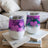 Two purple heart-patterned tumblers with clear lids on a book.