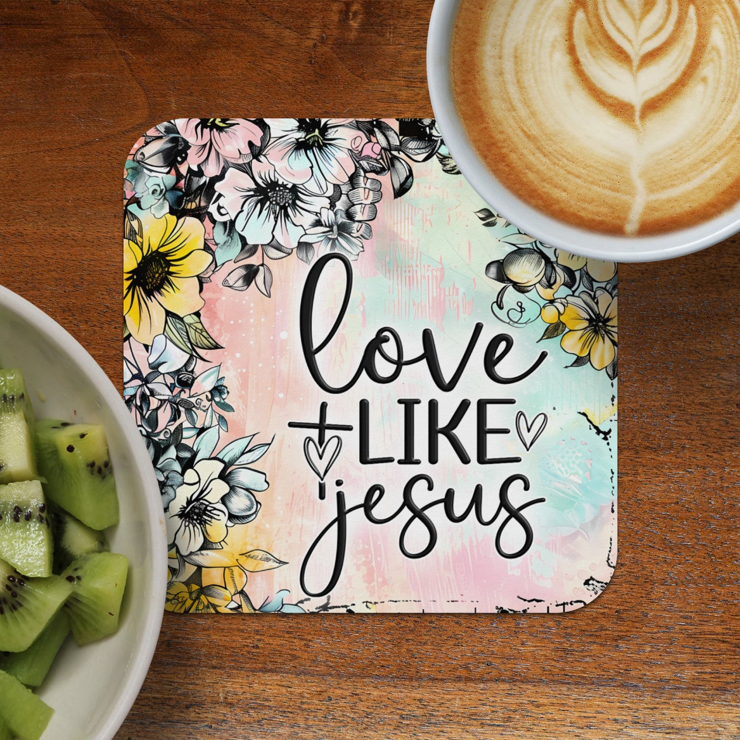 Coaster with "Love like Jesus" text and floral design, beside kiwi and coffee.