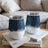 Two white tumblers with denim-inspired design and clear lids on books.