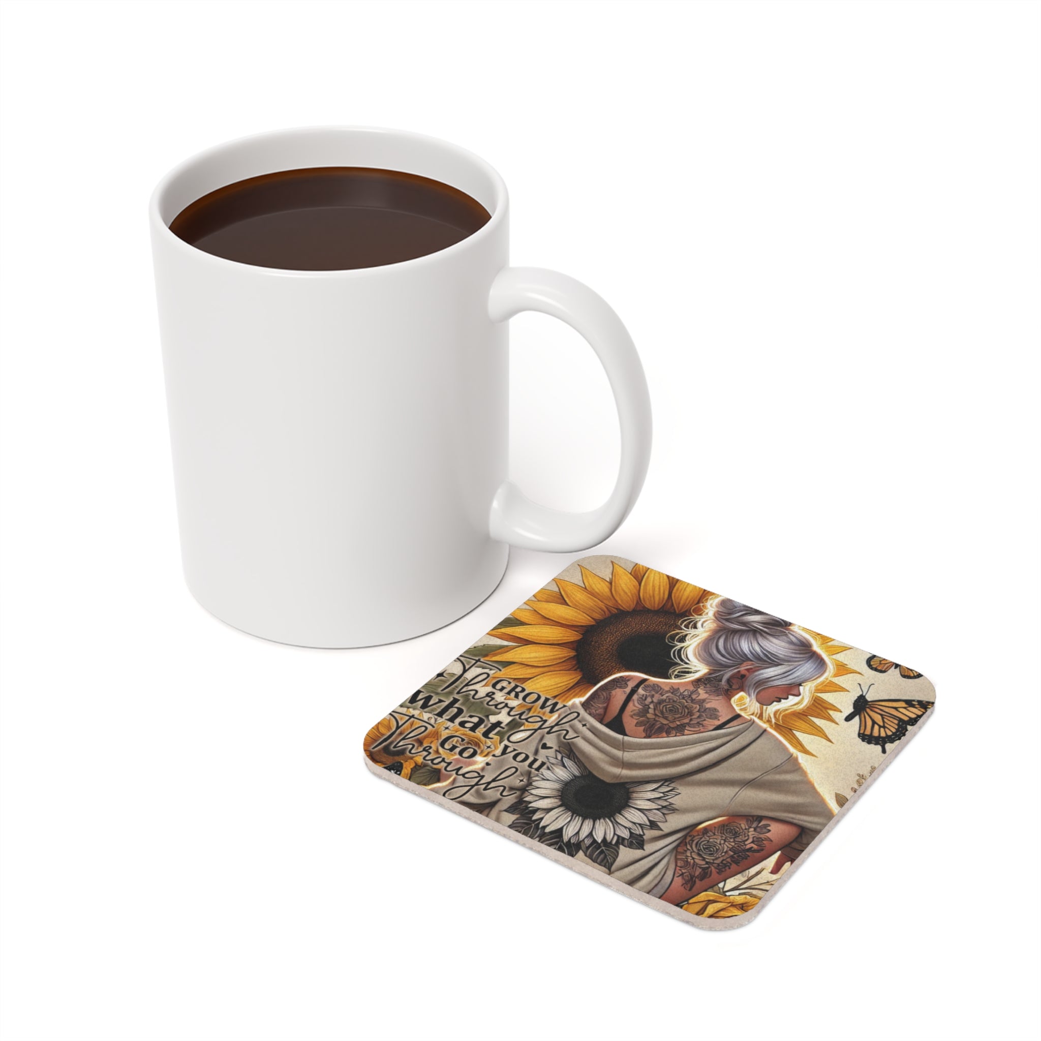 White mug with coffee next to a coaster featuring sunflowers and inspirational text.