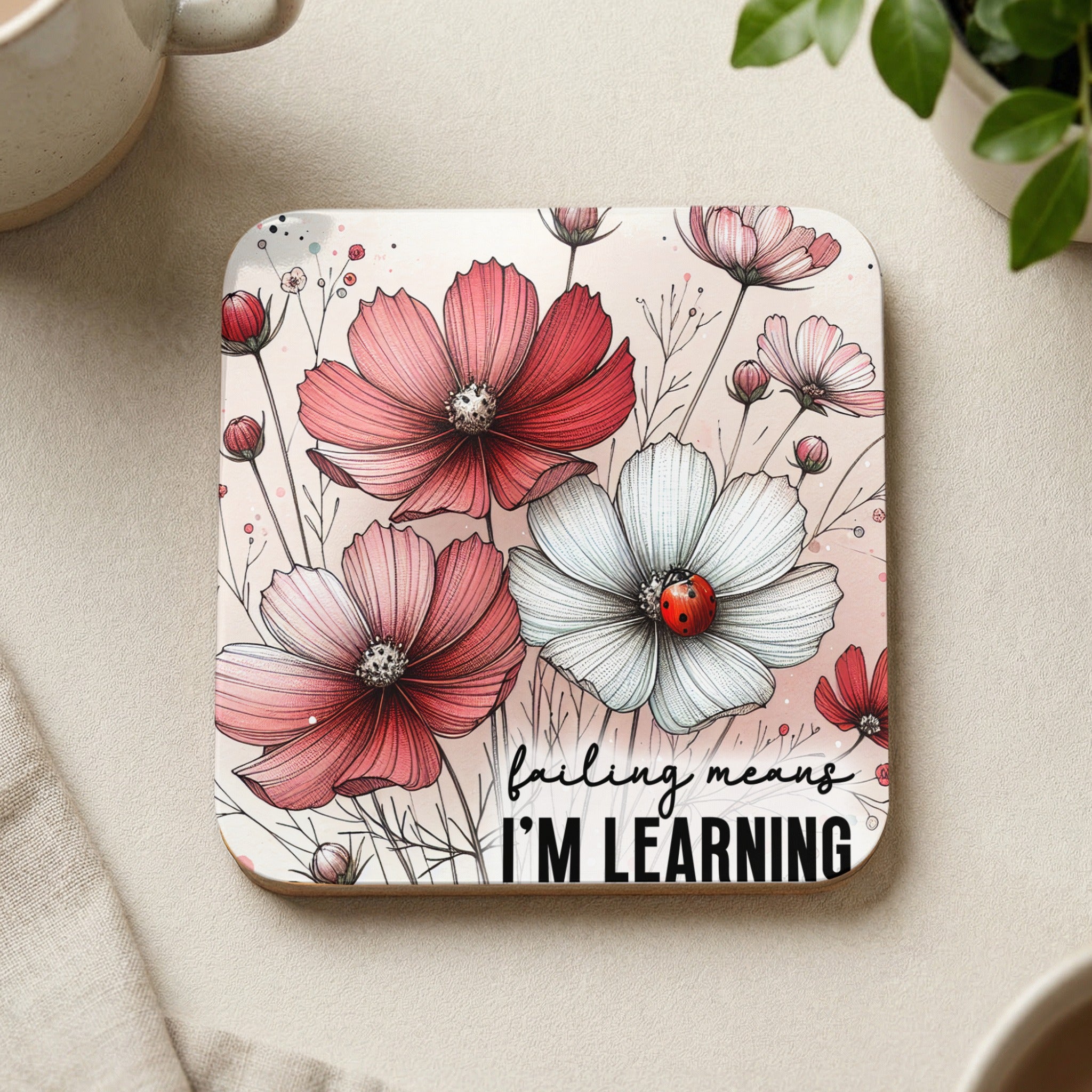 Square coaster with pink and white cosmos flowers and a ladybug, text "failing means I'M LEARNING".