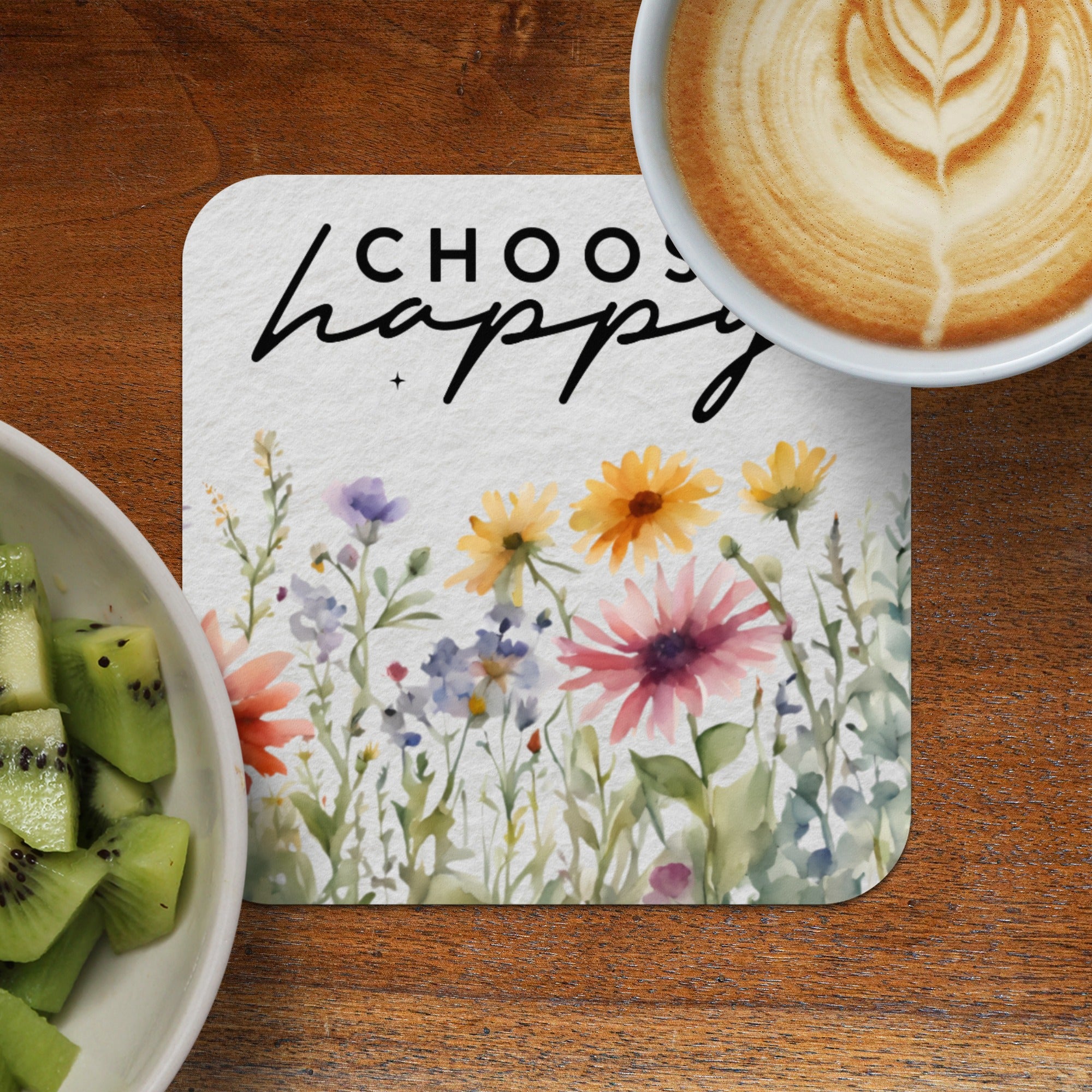Coaster with watercolor flowers and text "CHOOSE happy" next to a bowl of kiwi and coffee.