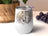 White tumbler with floral design of two horses' heads.