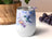 White tumbler with hummingbird and floral watercolor design, purple hearts.