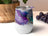 White tumbler with abstract purple, blue, and gold marbled design.