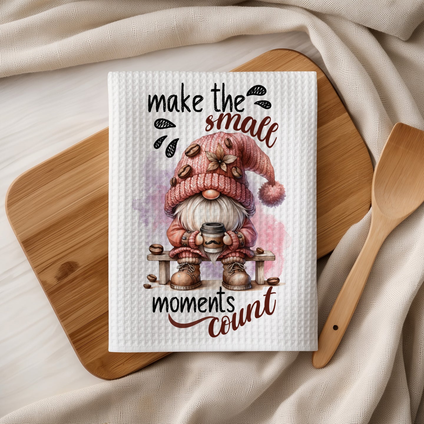 Gnome wearing a pink hat and scarf holding coffee cup with "make the small moments count" text.