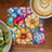 Colorful watercolor floral coasters on a wooden table with coffee and kiwi.