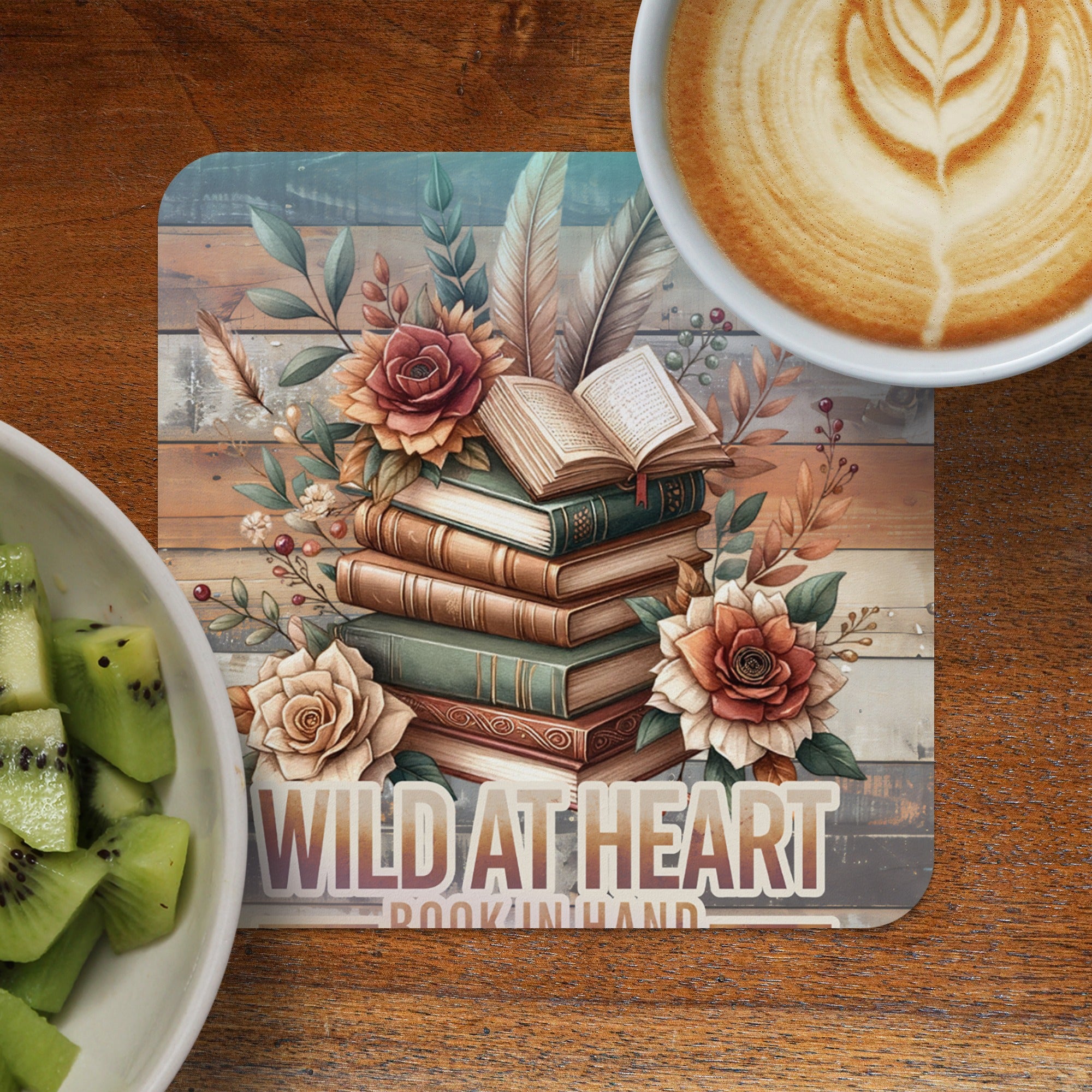 Stack of books with flowers and feathers, latte, and kiwi slices.