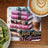 Stack of decorative pink books with bow and jewels next to coffee and kiwi slices.
