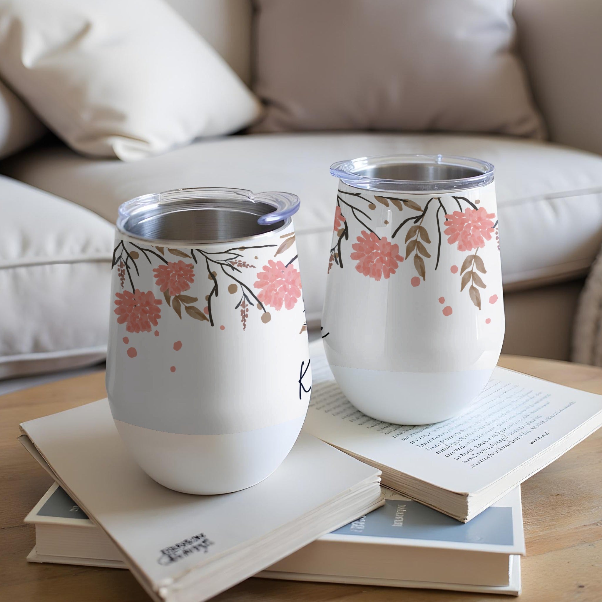 Two white floral tumblers with lids on a book.
