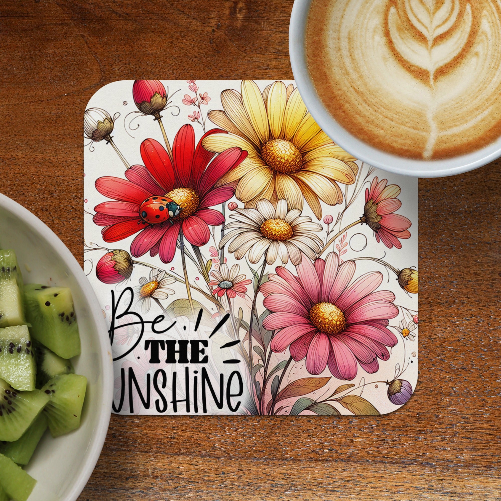 Coaster with bold red and pink flowers, a ladybug, and text "BE THE UNSHINE".