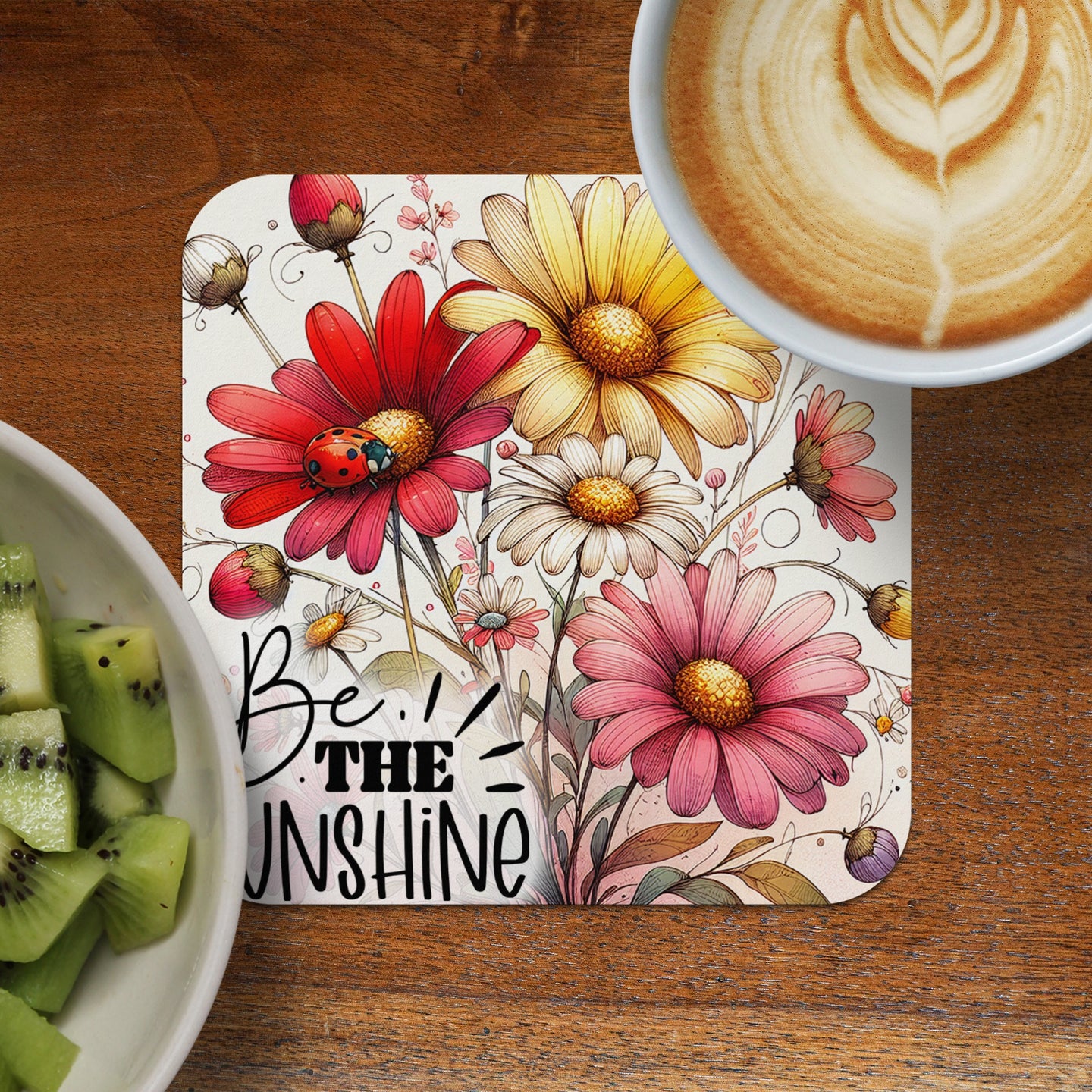 Coaster with bold red and pink flowers, a ladybug, and text "BE THE UNSHINE".