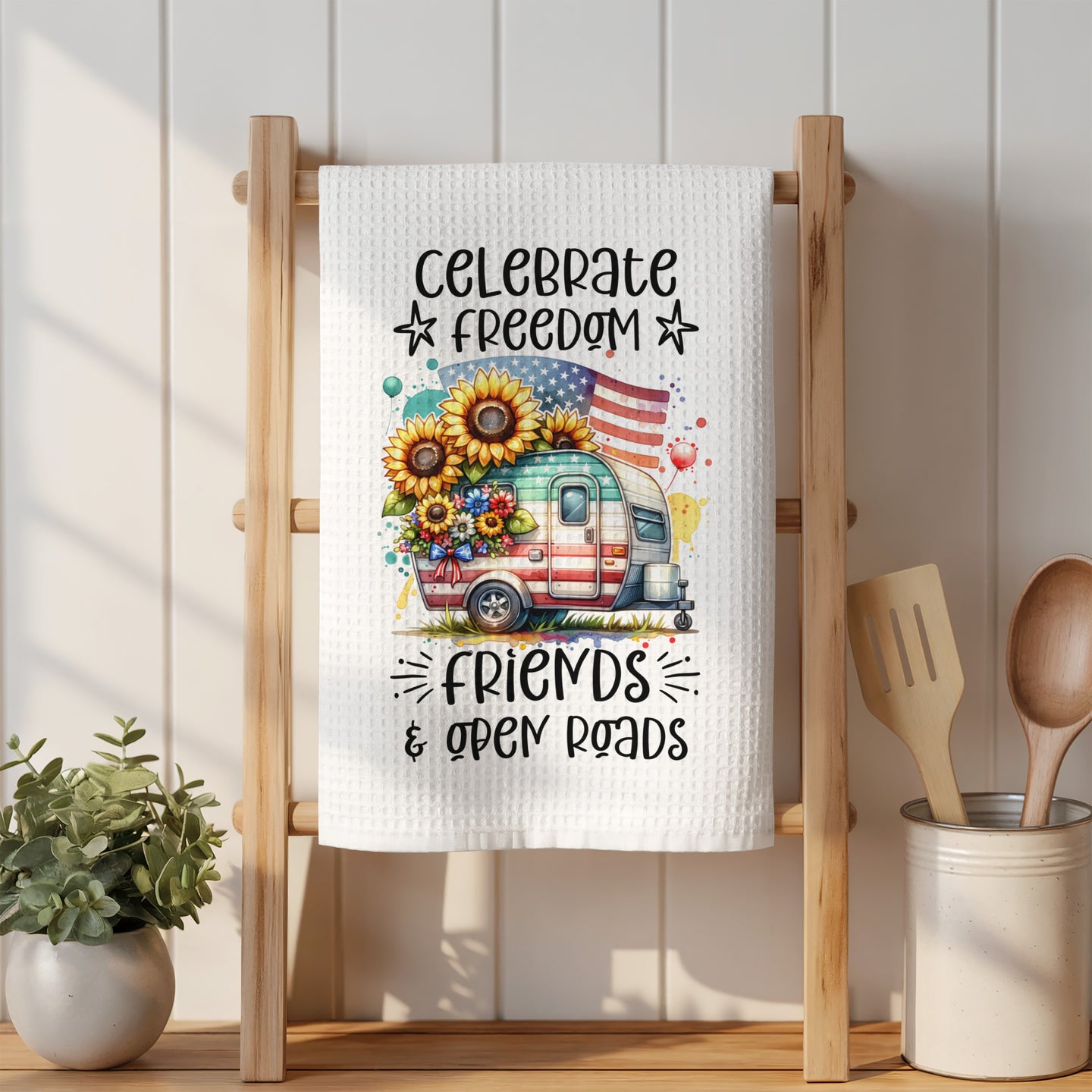 Camper with sunflowers and American flag, "Celebrate Freedom Friends & Open Roads" text.