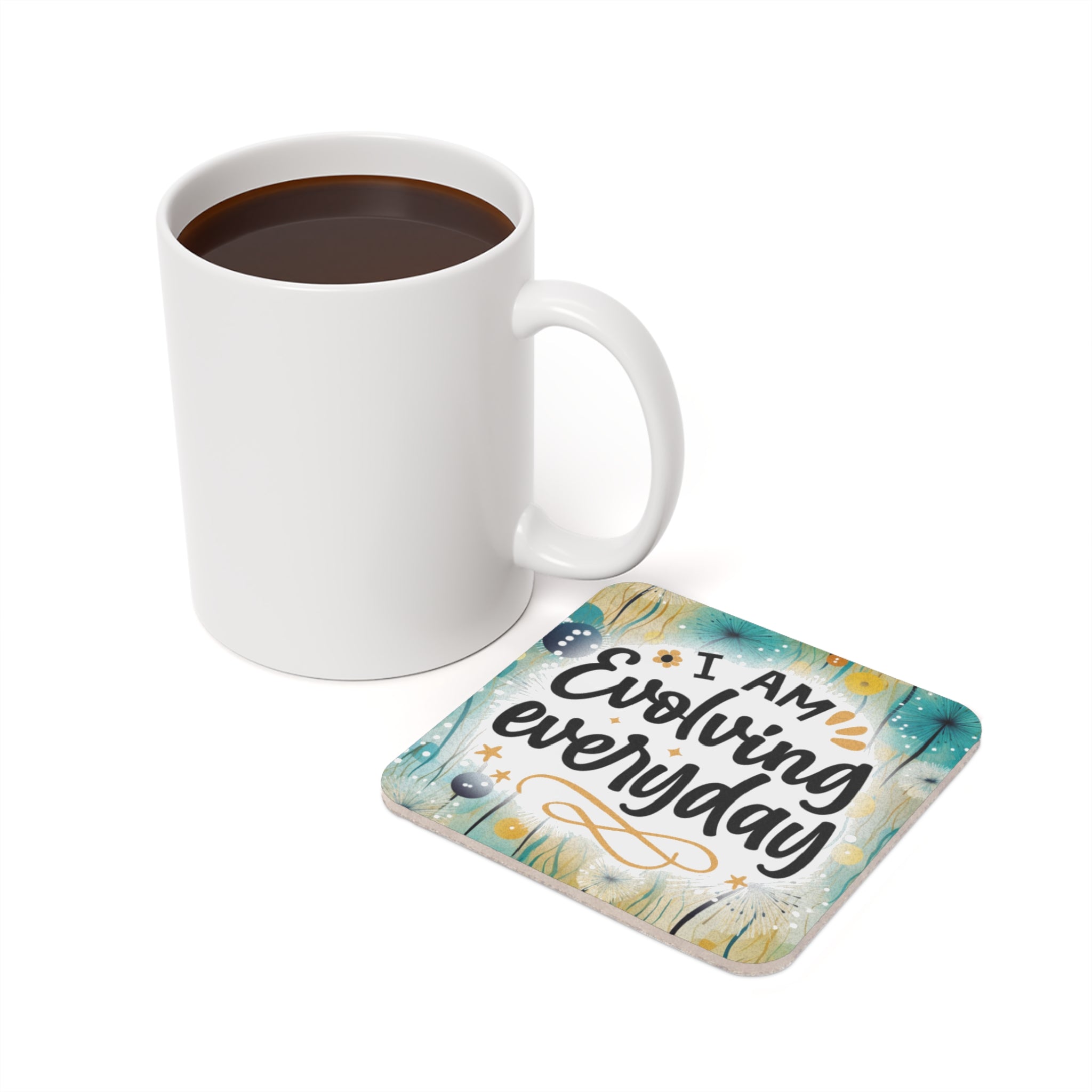 White mug of coffee next to a coaster with "I AM evolving everyday" text.