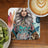 Woman with tattoos and "Never Stop Looking Up" text on coaster, with coffee and kiwi.
