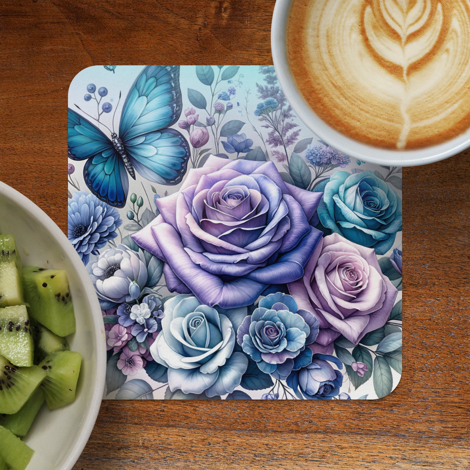 Blue butterfly and purple roses on a floral coaster next to kiwi slices and coffee.