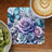 Blue butterfly and purple roses on a floral coaster next to kiwi slices and coffee.