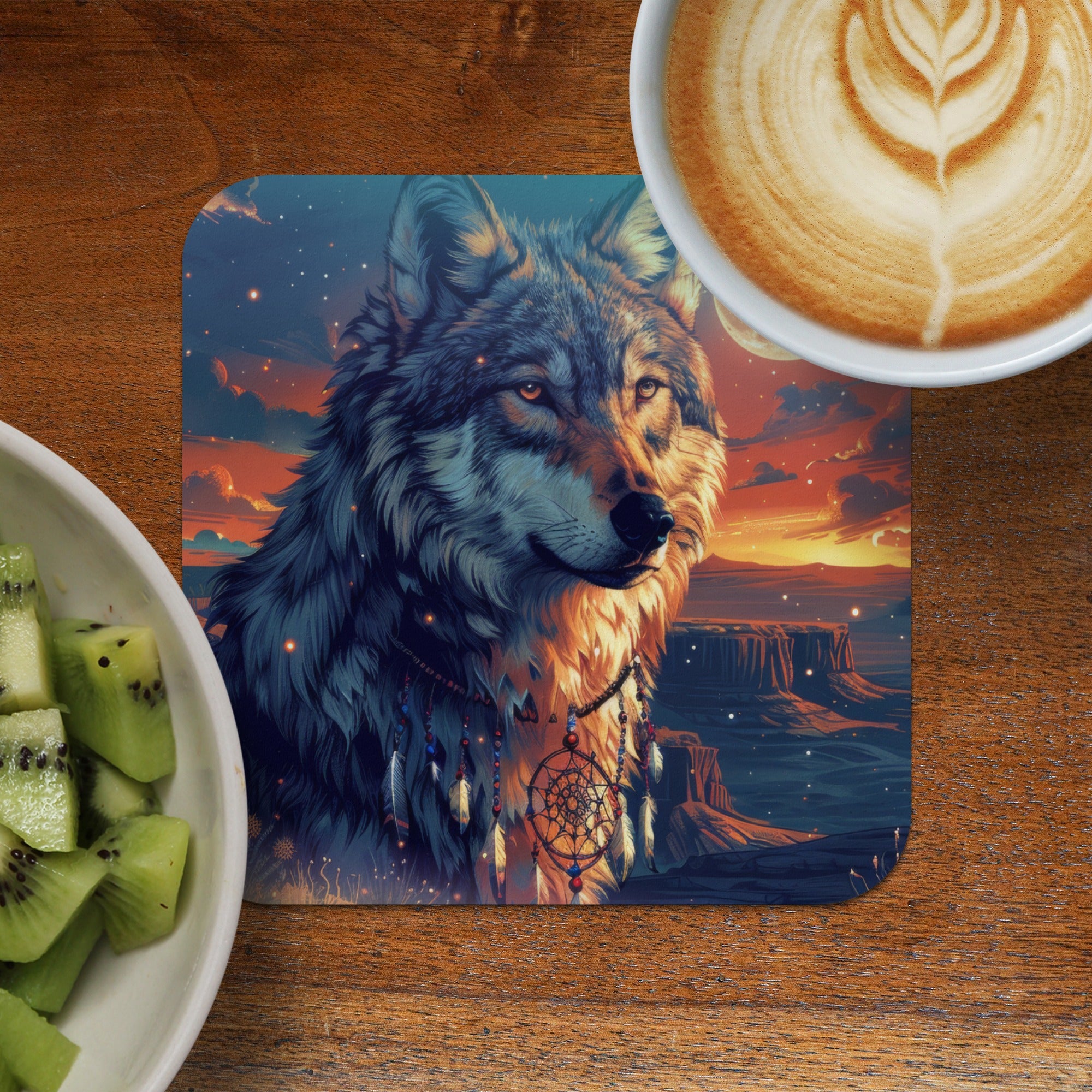 Wolf with dreamcatcher artwork on coaster next to kiwi and coffee.