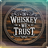 Circular wooden sign with "In Whiskey We Trust" text.