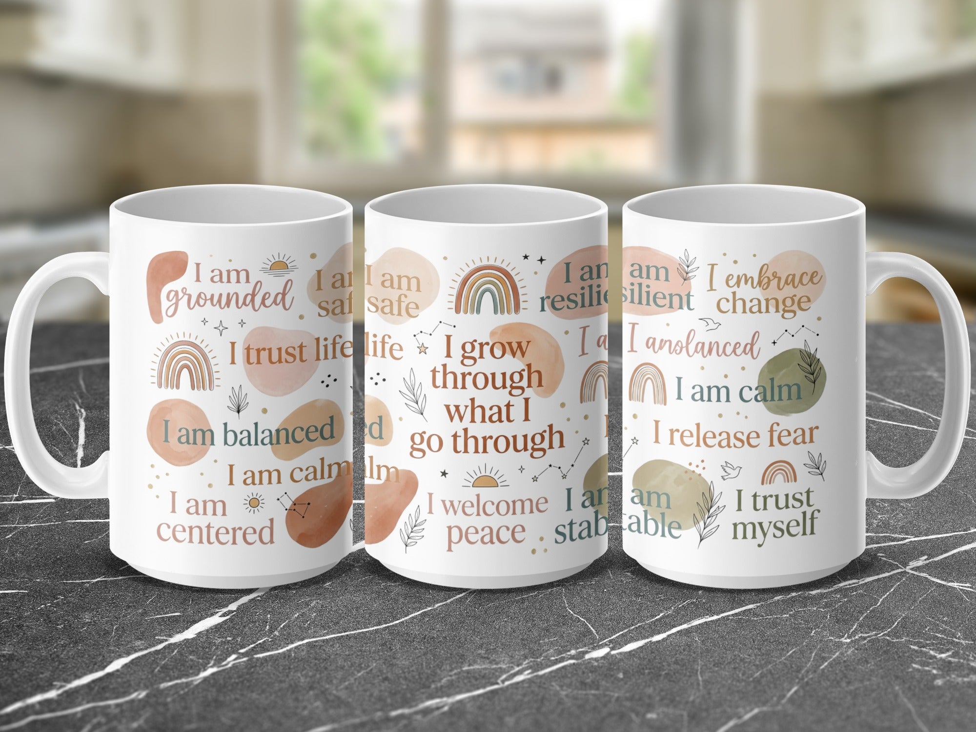 Three ceramic mugs displaying positive affirmations in a rainbow gradient.