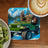 Bigfoot in a green Jeep giving peace sign with coffee and kiwi.