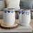 Two white tumblers with blue floral designs on a wooden coaster.