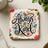 Square coaster with colorful floral and butterfly design and "Always Be Kind" text.