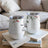 Two white tumblers with floral designs and text sit on books.