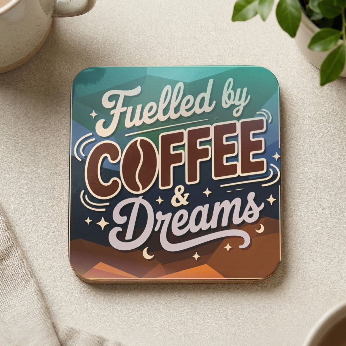 "Fuelled by Coffee & Dreams" text on a geometric patterned coaster.